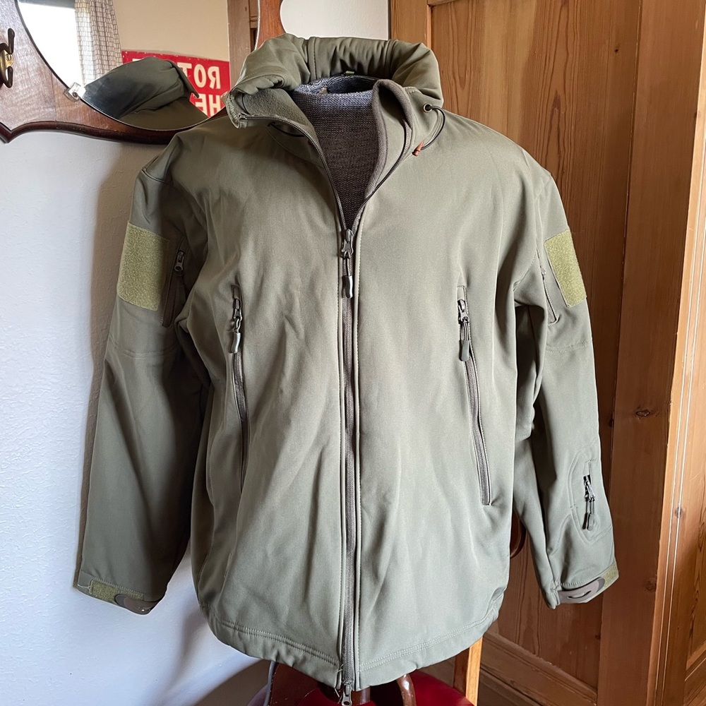 NWOT men's XXL tactical coat, stow-away billed hood. Pockets galore, vented arms